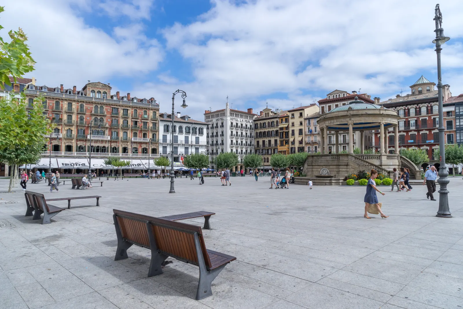 Plaza del Castillo de Pamplona con su quiosco, bancos de madera y edificios de varias plantas con balcones alrededor, entre ellos el Gran Hotel La Perla