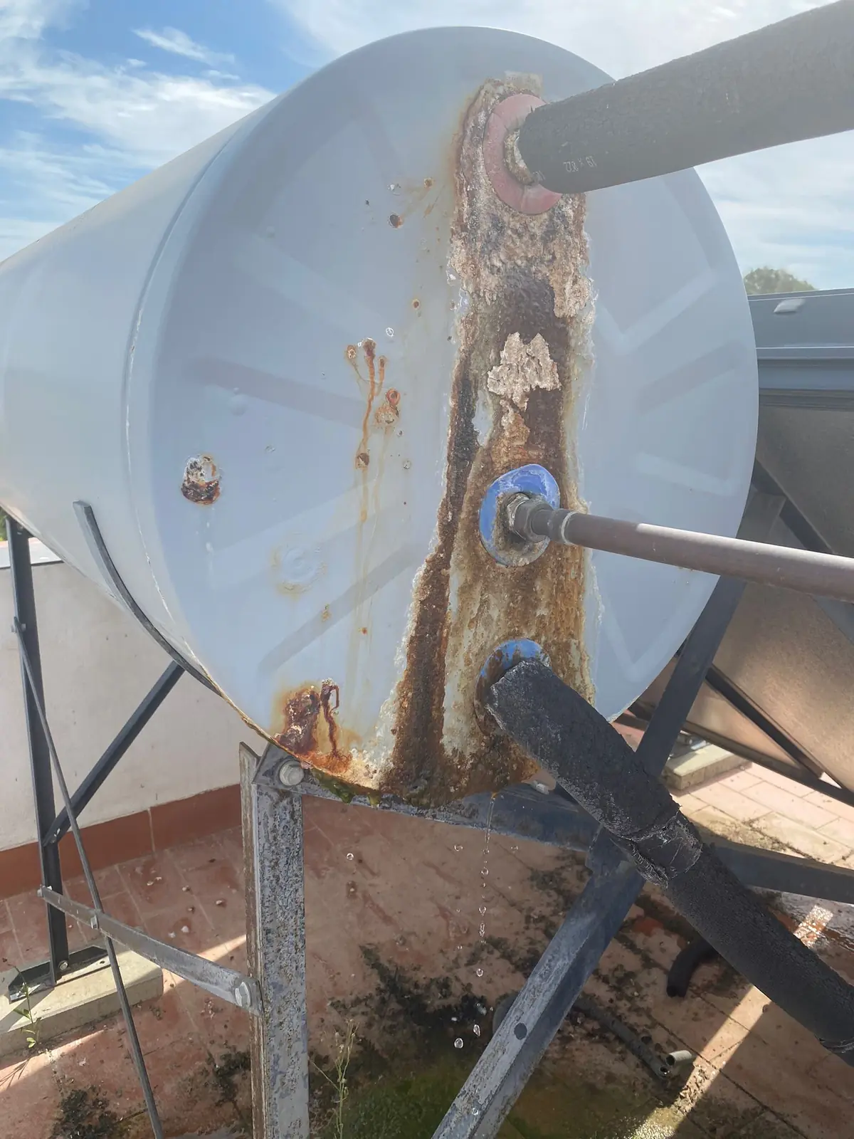 Depósito de agua caliente en una azotea con óxido y goteo por las conexiones